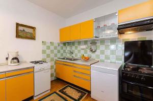 a kitchen with orange and white cabinets and a stove at Apartment in Jadranovo 39395 in Jadranovo
