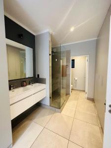 a bathroom with two sinks and a glass shower at Next to Brooklyn Mall Cosy stay in Pretoria