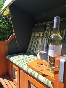 eine Flasche Wein mit einem Weinglas auf einer Bank sitzend in der Unterkunft Ferienhaus Landliebe in Riepsdorf