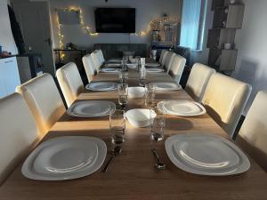 a long table with white plates and glasses on it at Liget Vendégház in Bélatanya