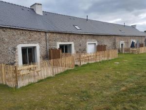 un edificio de ladrillo con una valla de madera delante de él en Gîte de penhaudan 3, en Pont-Scorff 3 fotos más