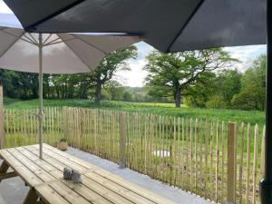 Un banco de madera con una sombrilla y una valla en Gîte de penhaudan 3, en Pont-Scorff