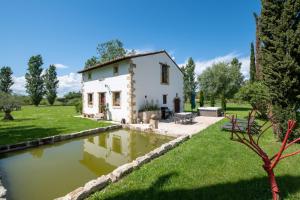 a country house with a pond in the yard at Mas des Eaux Claires Arles Camargue in Saint-Gilles