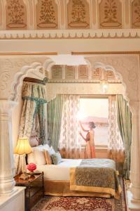 a woman standing in a bedroom looking out the window at Taj Lake Palace Udaipur in Udaipur