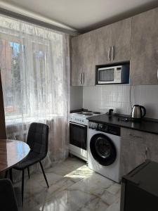 a kitchen with a washing machine and a microwave at Апартаменты в центре города Балхаш in Balqash