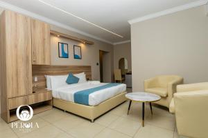 une chambre d'hôtel avec un lit et une chaise dans l'établissement PEROLA HOTEl, à Maputo