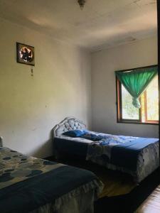 ein Schlafzimmer mit zwei Betten und einem Fenster in der Unterkunft Villa Rian Argapuri Resort in Gambung