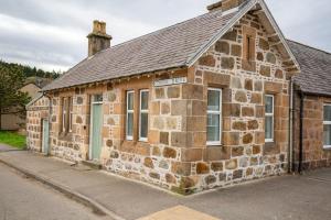 an old stone building on the side of a street at West Lodge, High Street in Aberlour