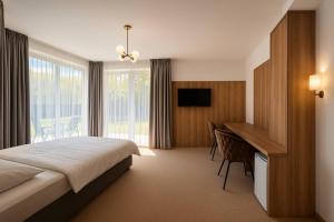 a bedroom with a bed and a desk and a television at Eden Apartament Jakuzzi, sauna in Rozewie