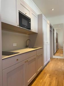 a kitchen with white cabinets and a sink and a microwave at Gartenvilla in Marktheidenfeld