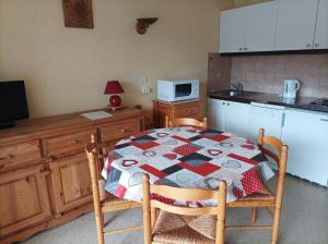 a kitchen with a table with a quilt on it at Charmant studio au coeur du village in Prémanon