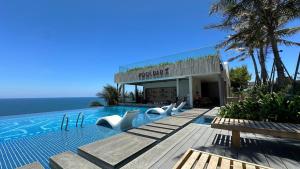 a swimming pool with white chairs in front of a building at Apec Mandala Muine in Mui Ne