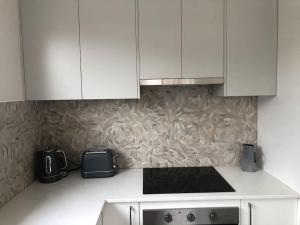a kitchen with white cabinets and a stove top oven at Cozy on Clinton in Orange