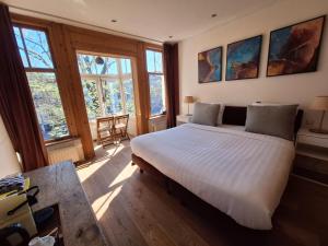 ein Schlafzimmer mit einem großen weißen Bett in einem Zimmer mit Fenstern in der Unterkunft A B&B Amsterdam in Amsterdam