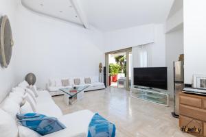 un salon avec des meubles blancs et une télévision à écran plat dans l'établissement Villa Prestige Hammam & Piscine, à Cannes
