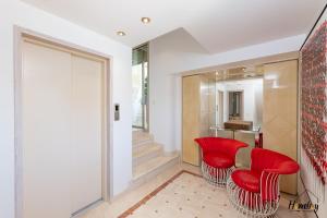 un salon avec des fauteuils rouges et un escalier dans l'établissement Villa Prestige Hammam & Piscine, à Cannes