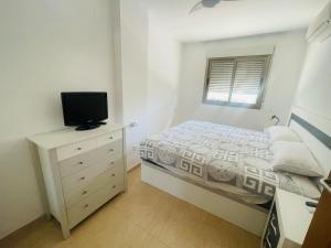 a bedroom with a bed and a dresser with a television at Cozy apartment in Benidorm in Villajoyosa +5 photos