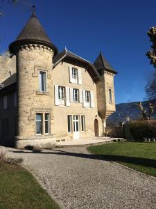 ein großes Steinhaus mit einem Turm auf einer Auffahrt in der Unterkunft Domaine du Valromey in Champagne-en-Valromey