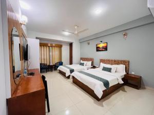 a hotel room with two beds and a flat screen tv at Sylhet Paradise Inn in Sylhet