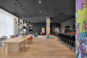 Un comedor con mesas y sillas y un bar. en IntercityHotel Breda, en Breda