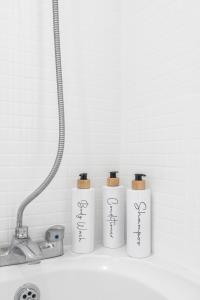 drei weiße Flaschen auf einem Regal neben einem Waschbecken in der Unterkunft Regents House, Brighton in Brighton & Hove + 14 Fotos