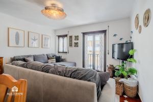 Una sala de estar con un sofá y un televisor. en Azenha Beach House - Sea view with BBQ, en Santa Cruz