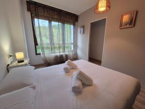 a bedroom with two towels on a bed with a window at 33A02 Amplio apartamento en Tuilla in Langreo +14 photos