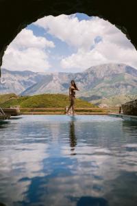 a woman walking in a pool of water with mountains in the background at Villa Si Era in Brataj +161 photos