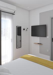 a white bedroom with a tv and a bed at Lᾶs Serifos in Livadi