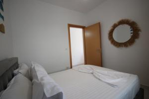 a white bed in a room with a mirror at IonianBlue Apartament I in Himare