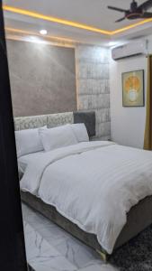 a bedroom with a large bed with white sheets at Nems Appartment in Ikeja
