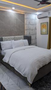 a bedroom with a large bed with white sheets at Nems Appartment in Ikeja