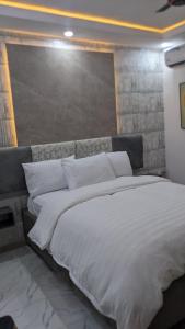 a large bed with white sheets and pillows at Nems Appartment in Ikeja