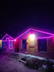 una casa con luces rosas en la parte delantera en Parvati Hill Cottage By Soma Stays, en Kasol