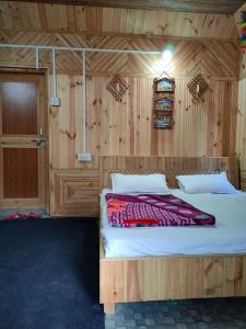 Un dormitorio con una cama en una habitación de madera. en Parvati Hill Cottage By Soma Stays, en Kasol