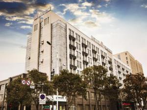 a large white building with trees in front of it at Jinjiang Inn Yancheng Funing Harbin Road in Yancheng