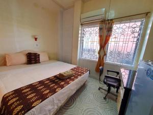 a small bedroom with a bed and a window at Hotel Sinar Khatulistiwa in Singkawang
