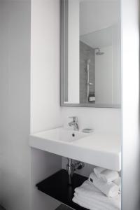 a white bathroom with a sink and a mirror at Alex Hotel in Perth