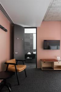 a living room with a chair and a table and a tv at Alex Hotel in Perth