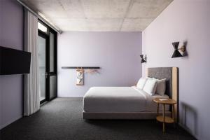 a white bedroom with a bed and a tv at Alex Hotel in Perth