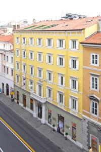 un bâtiment jaune sur le côté d'une rue dans l'établissement Hotel Roma, à Trieste