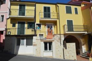 a woman standing on the balcony of a yellow building at Gafo da Longa in Satriano
