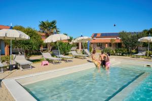 un gruppo di persone in piedi in acqua in una piscina di Delfino Tuscany Resort a Marina di Cecina