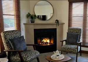 a living room with two chairs and a fireplace at Sandstone Suites - In the heart of Port Fairy in Port Fairy