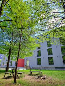 two picnic tables in a park in front of a building at Plně vybavený apartmán pod Mumlavským vodopádem, ZAHRADA s ohništěm, ideální výchozí bod pro TURISTIKU, kousek do CENTRA, vybavený i pro DĚTI in Harrachov