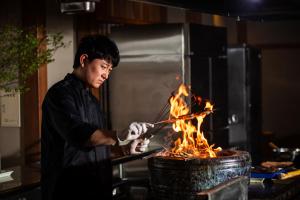 a man is cooking over a fire in a pot at Atarayo Nishiizu Onsen in Ukusu