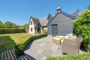 a patio with two chairs and a house at The Folly, Thorpe Forest in Brettenham