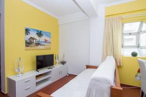 アルマカオ・デ・ペラにあるAkisol Armação Pera Beach IVの黄色のベッドルーム(ベッド1台、テレビ付)