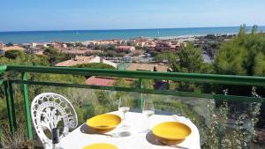 a table with yellow chairs and a view of the ocean at Appartement dans maison sur la Falaise in Leucate-Plage