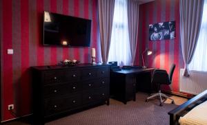 a bedroom with a desk and a dresser with a television on the wall at Restaurace Stará Lípa in Česká Lípa